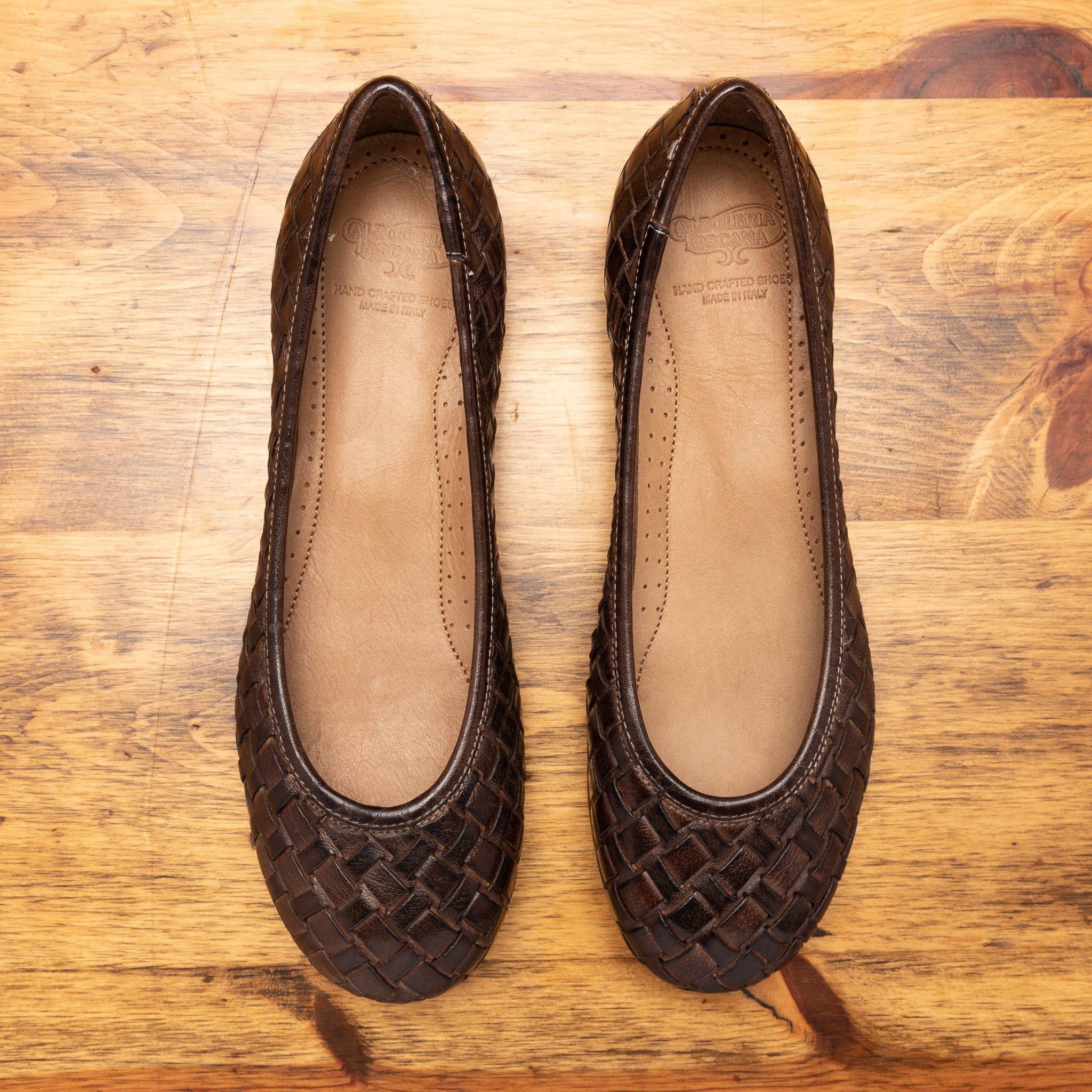 Pair of Tobacco woven flat shoe on a wooden surface