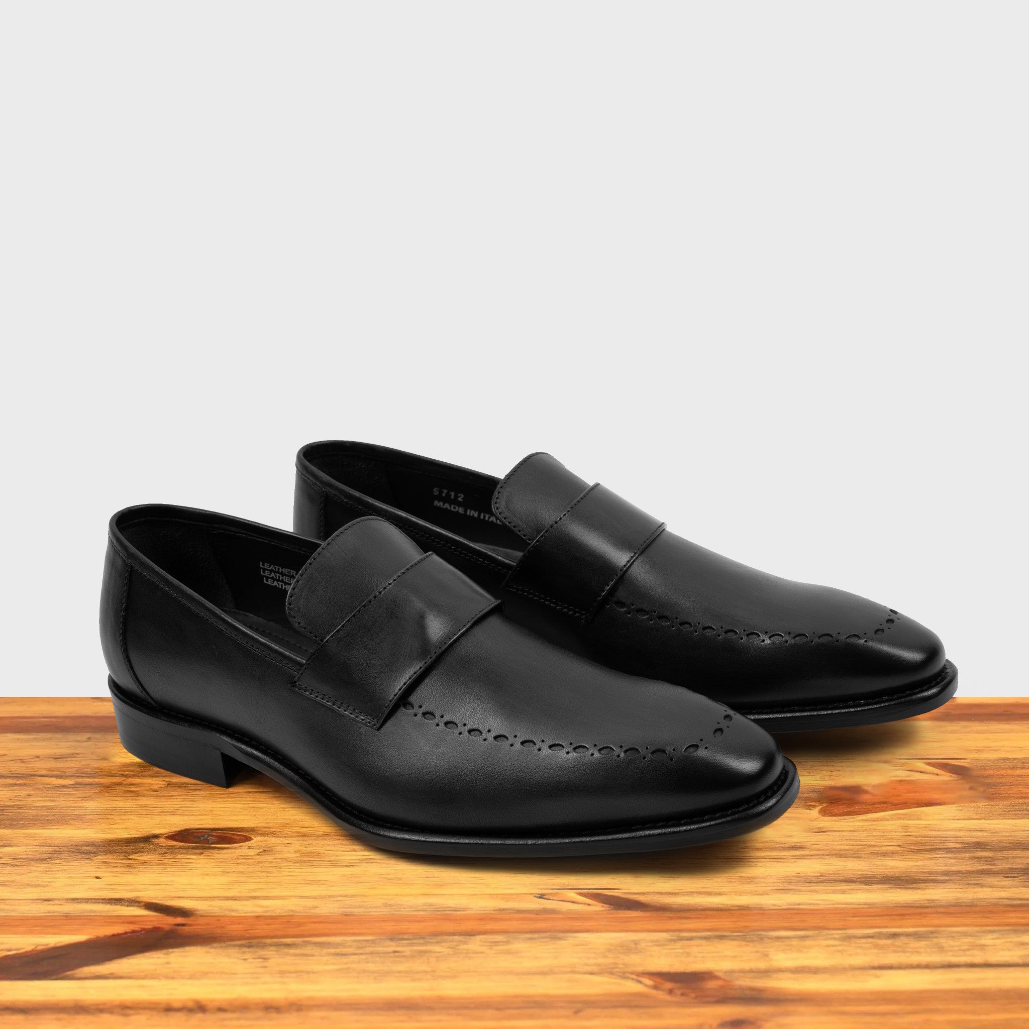 A Pair of Black leather loafer on a wooden surface 