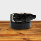 Black textured belt with a silver buckle on a wooden surface
