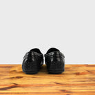 A Pair of Black leather loafer on a wooden surface with a white background