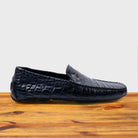 Blue crocodile-patterned loafer on a wooden surface with a light gray background