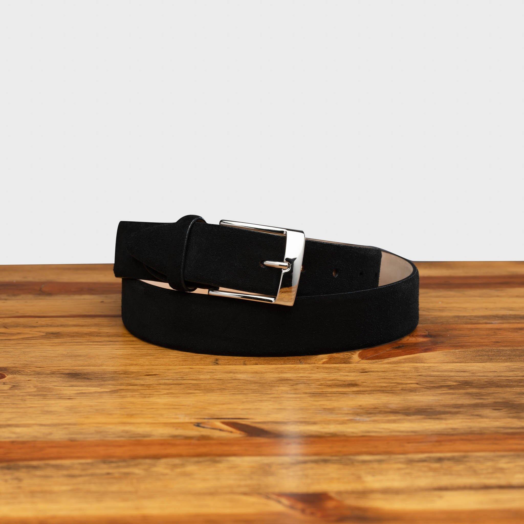 Black belt with a silver buckle on a wooden surface