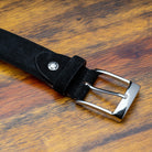 Black belt with a silver buckle on a wooden surface