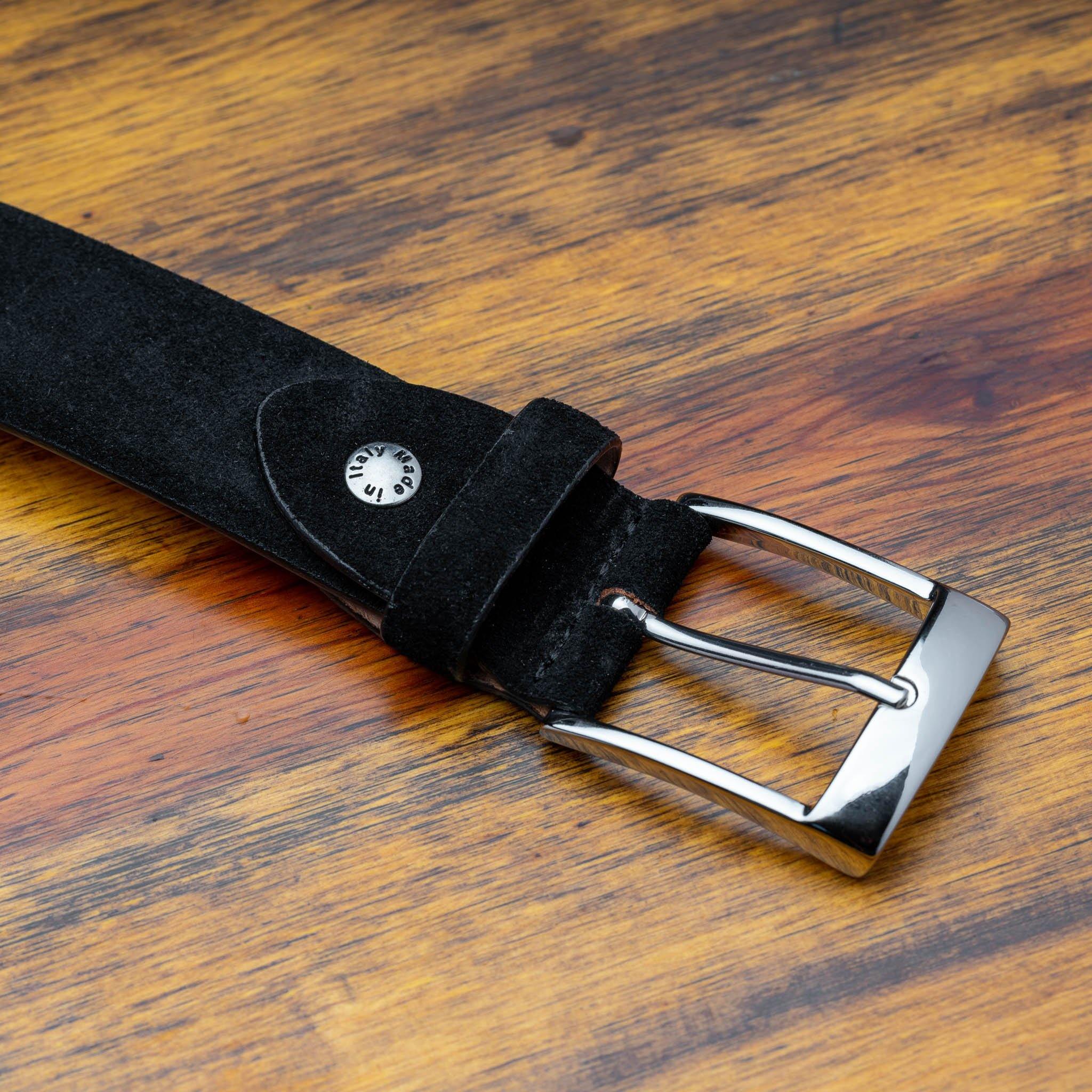 Black belt with a silver buckle on a wooden surface