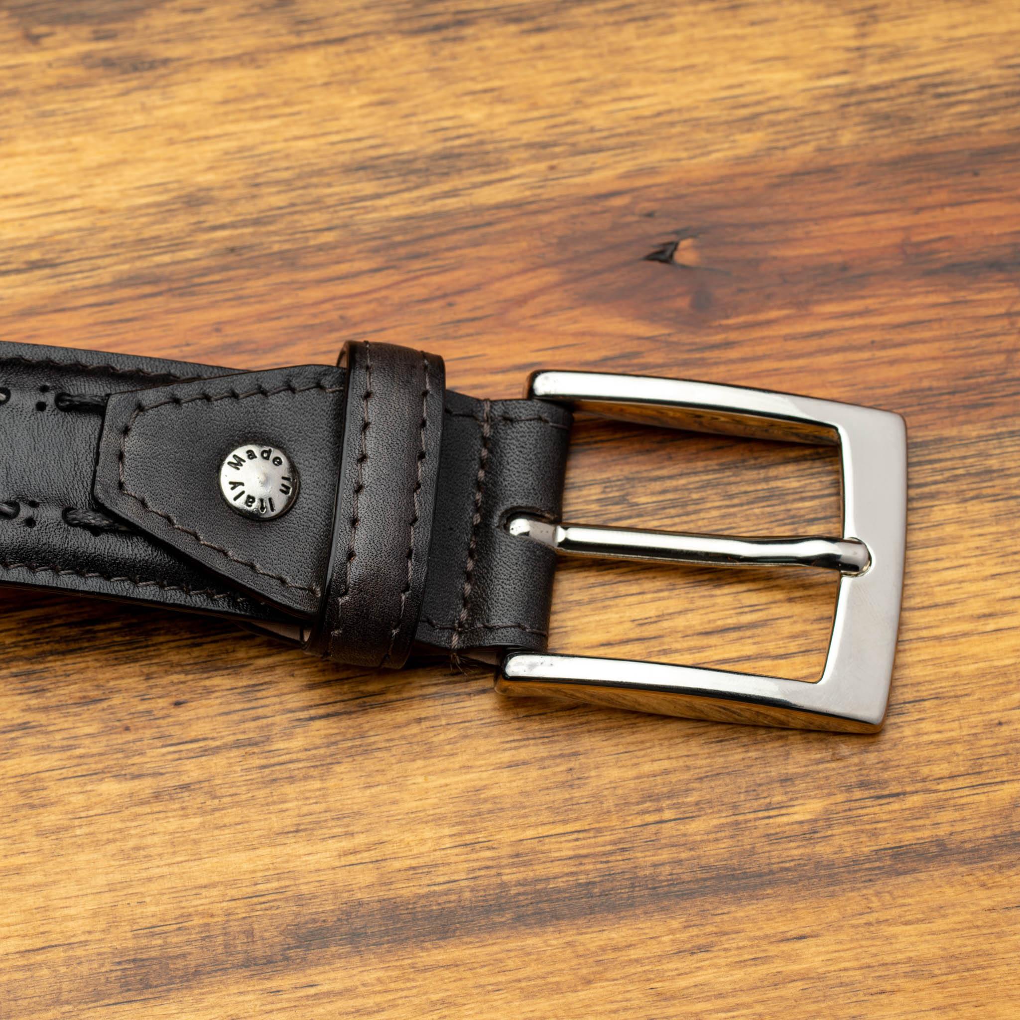 Black leather belt with a silver buckle on a wooden surface
