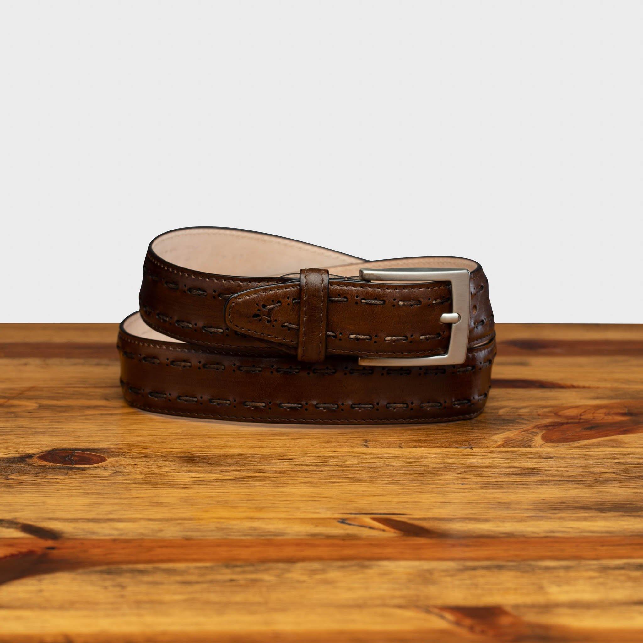 Mahogany leather belt with a silver buckle on a wooden surface