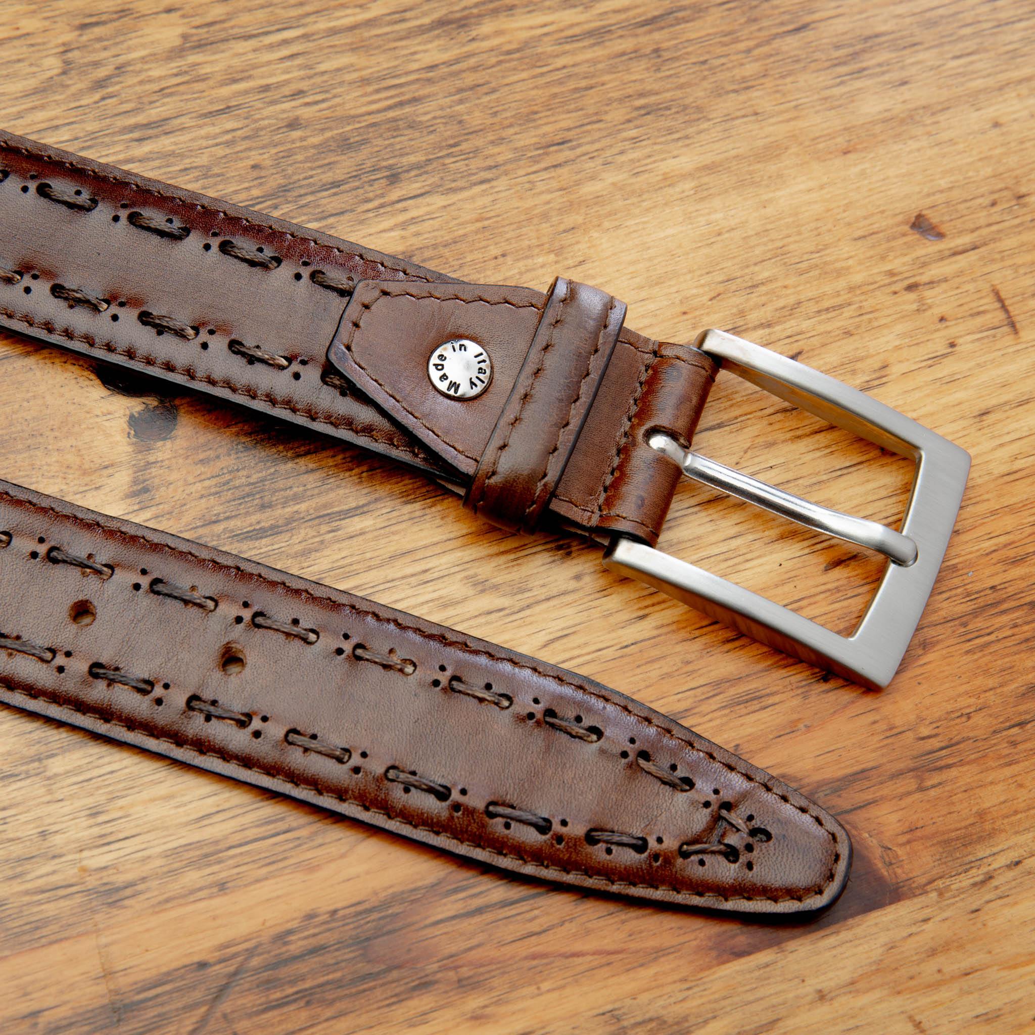 Mahogany leather belt with a silver buckle on a wooden surface