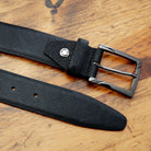 Black belt with a silver buckle on a wooden surface
