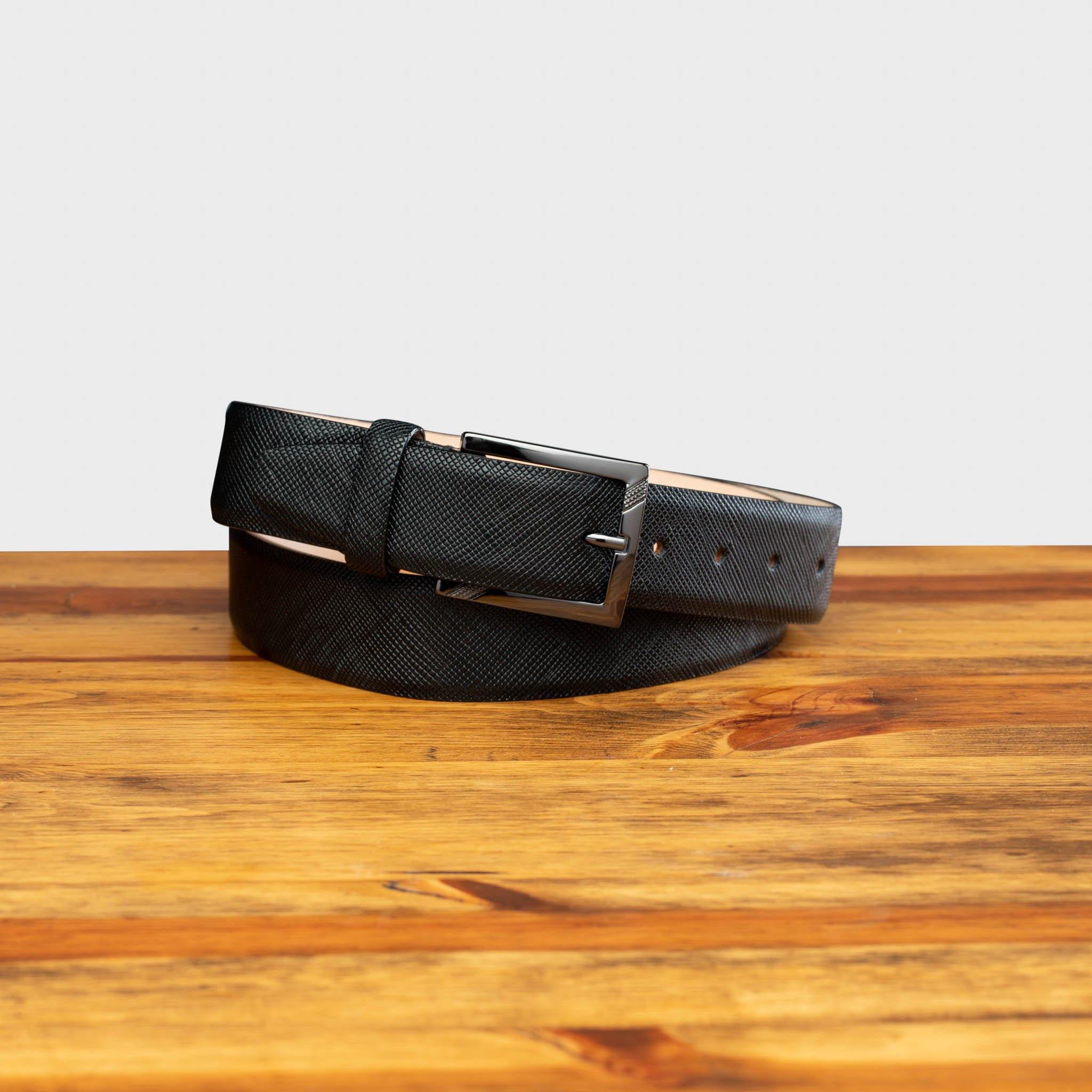 Black belt with a silver buckle on a wooden surface