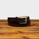 Brown belt with a silver buckle on a wooden surface