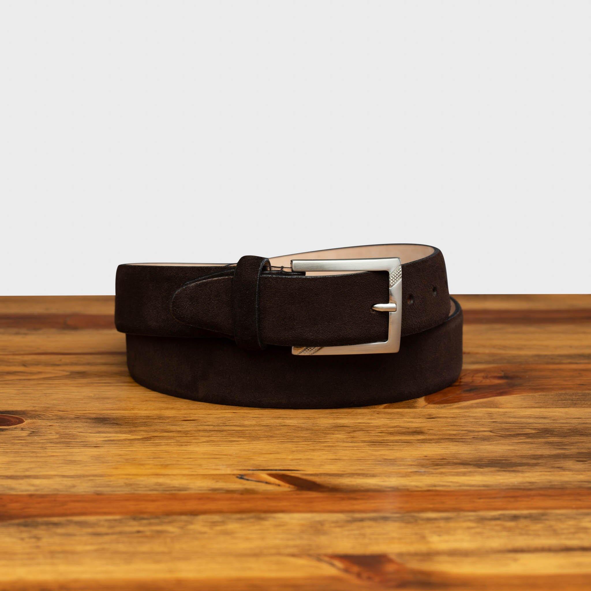 Brown belt with a silver buckle on a wooden surface