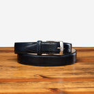 Blue leather belt with silver buckle on a wooden surface