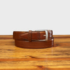 Dark Caramel leather belt with silver buckle on a wooden surface
