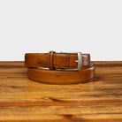 Chestnut leather belt with silver buckle on a wooden surface