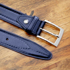 Blue leather belt with a silver buckle on a wooden surface