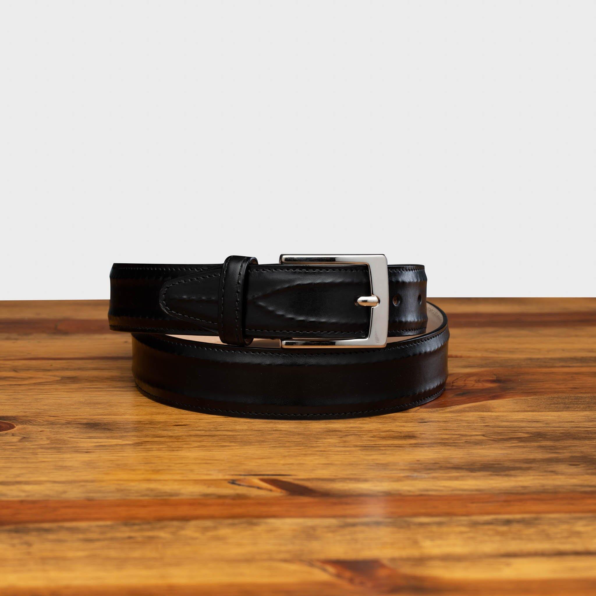 Black leather belt with a silver buckle on a wooden surface