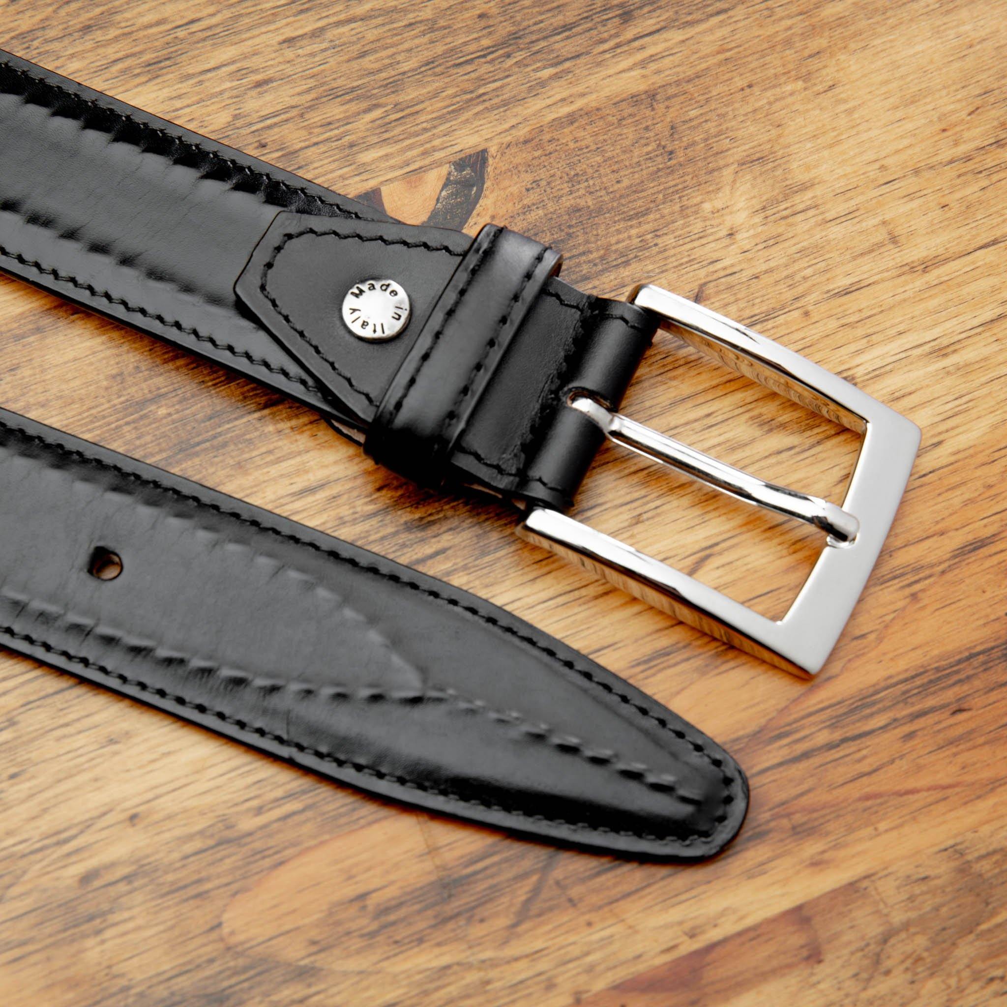 Black leather belt with a silver buckle on a wooden surface