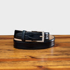 Blue leather belt with a silver buckle on a wooden surface