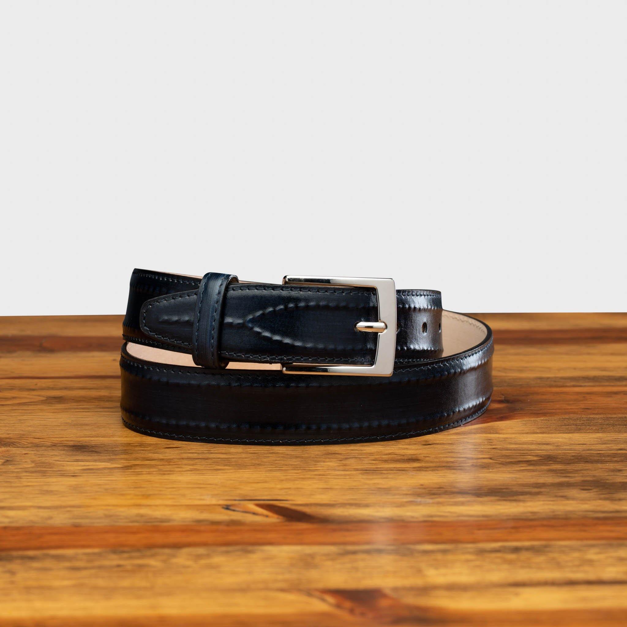 Blue leather belt with a silver buckle on a wooden surface