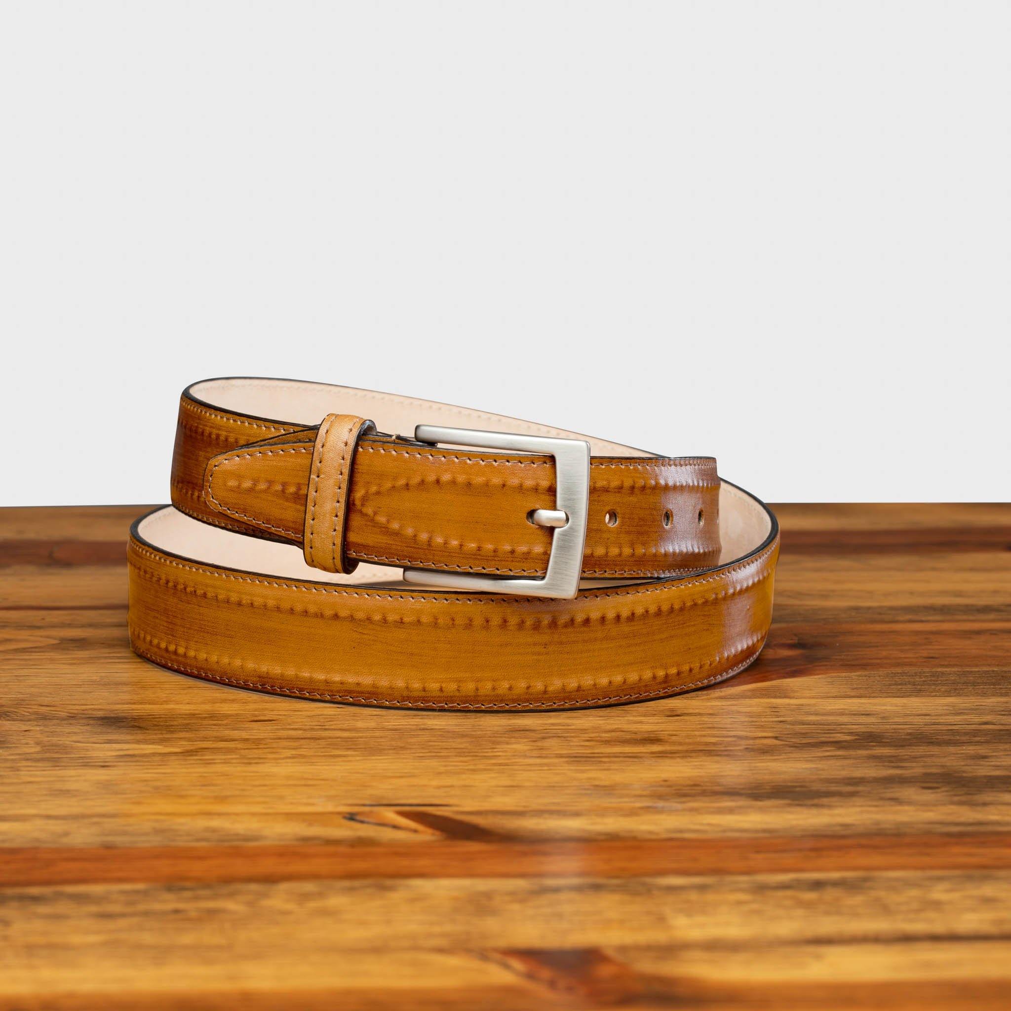 Chestnut leather belt with a silver buckle on a wooden surface