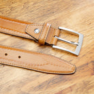Chestnut leather belt with a silver buckle on a wooden surface