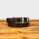 Dark Brown leather belt with a silver buckle on a wooden surface
