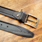 Dark Brown leather belt with a silver buckle on a wooden surface