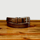 Brown  leather belt with a silver buckle on a wooden surface