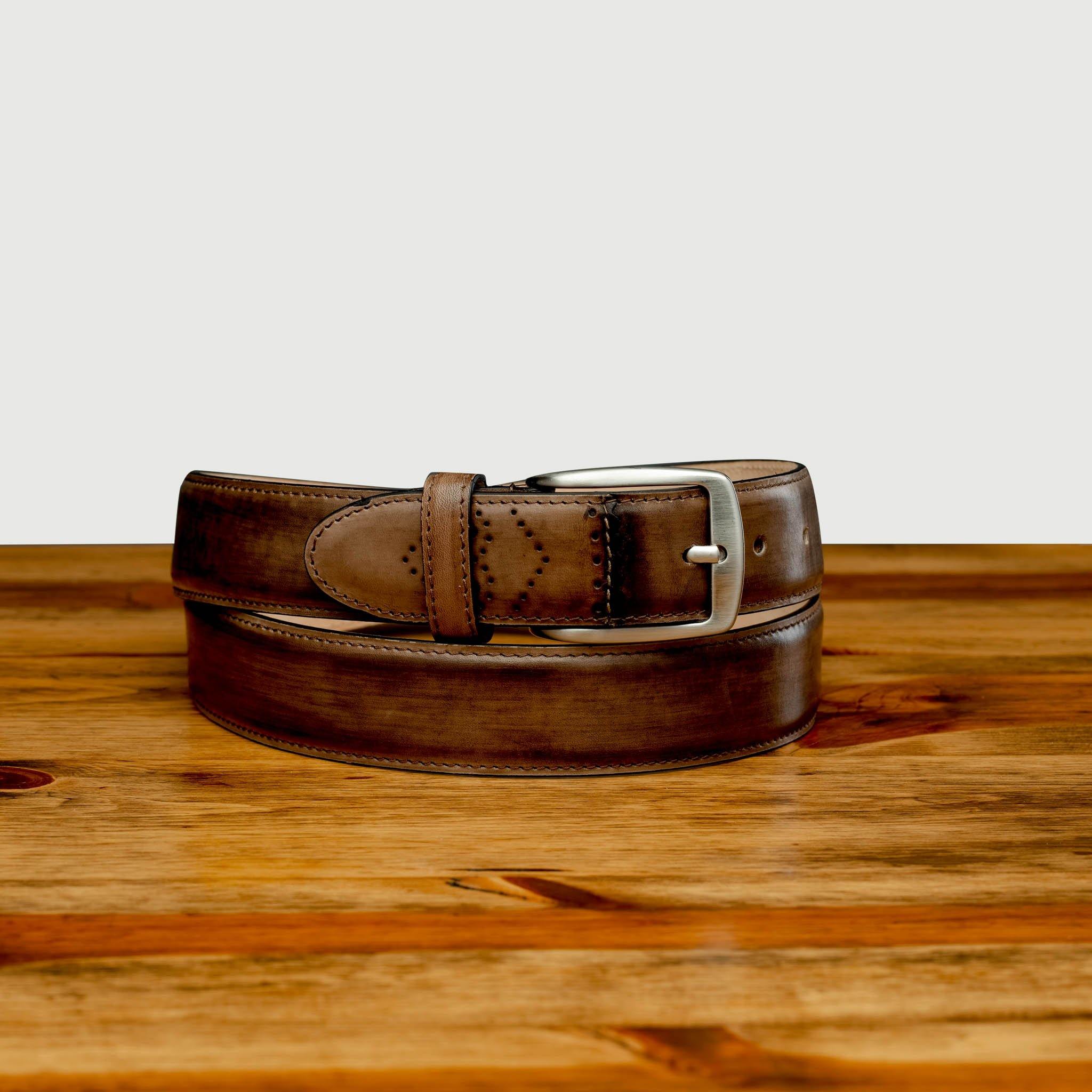 Brown  leather belt with a silver buckle on a wooden surface