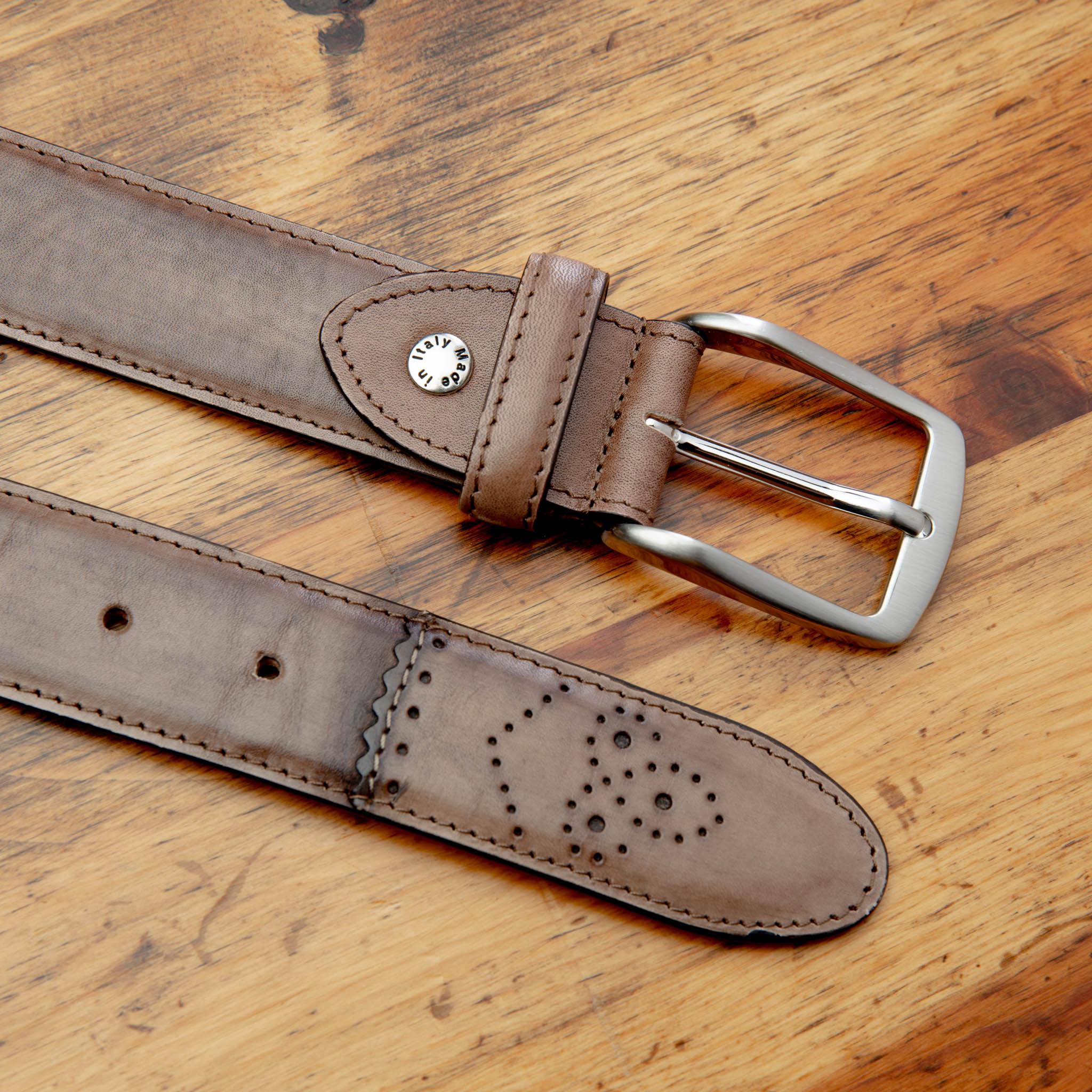Brown leather belt with a silver buckle on a wooden surface