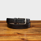 Graphite leather belt with a silver buckle on a wooden surface