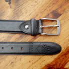 Graphite leather belt with a silver buckle on a wooden surface