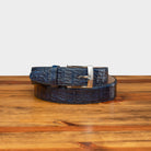 A navy blue genuine exotic hornback belt with a silver buckle on a wooden surface.