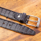 A brown genuine exotic hornback belt with a silver buckle on a wooden surface.