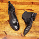 Pair of black leather Chelsea boots on a wooden surface