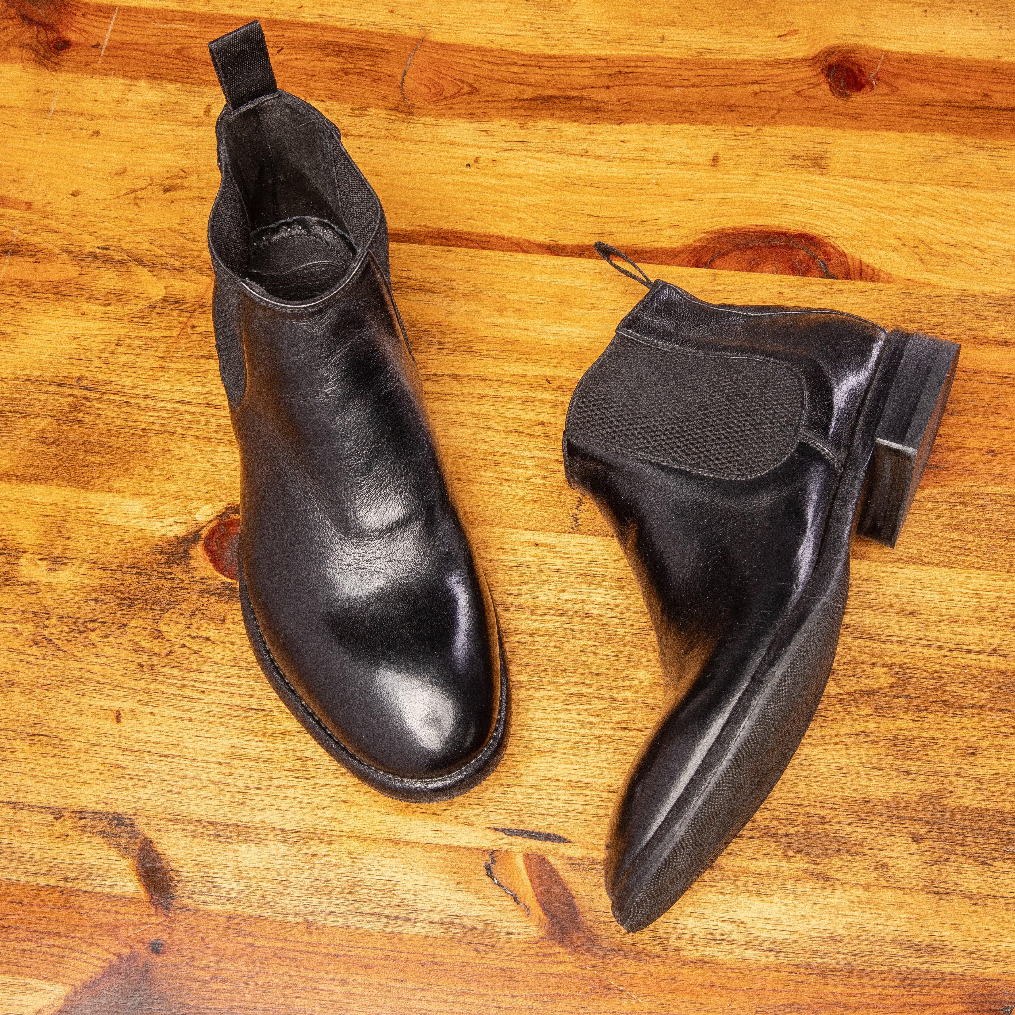 Pair of black leather Chelsea boots on a wooden surface