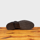 Outsole of black leather Chelsea boots on a wooden surface with a light gray background