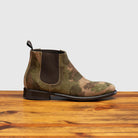 Camouflage-patterned boot on a wooden surface with a light gray background