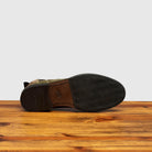 Outsole of Camouflage-patterned boot on a wooden surface with a light gray background