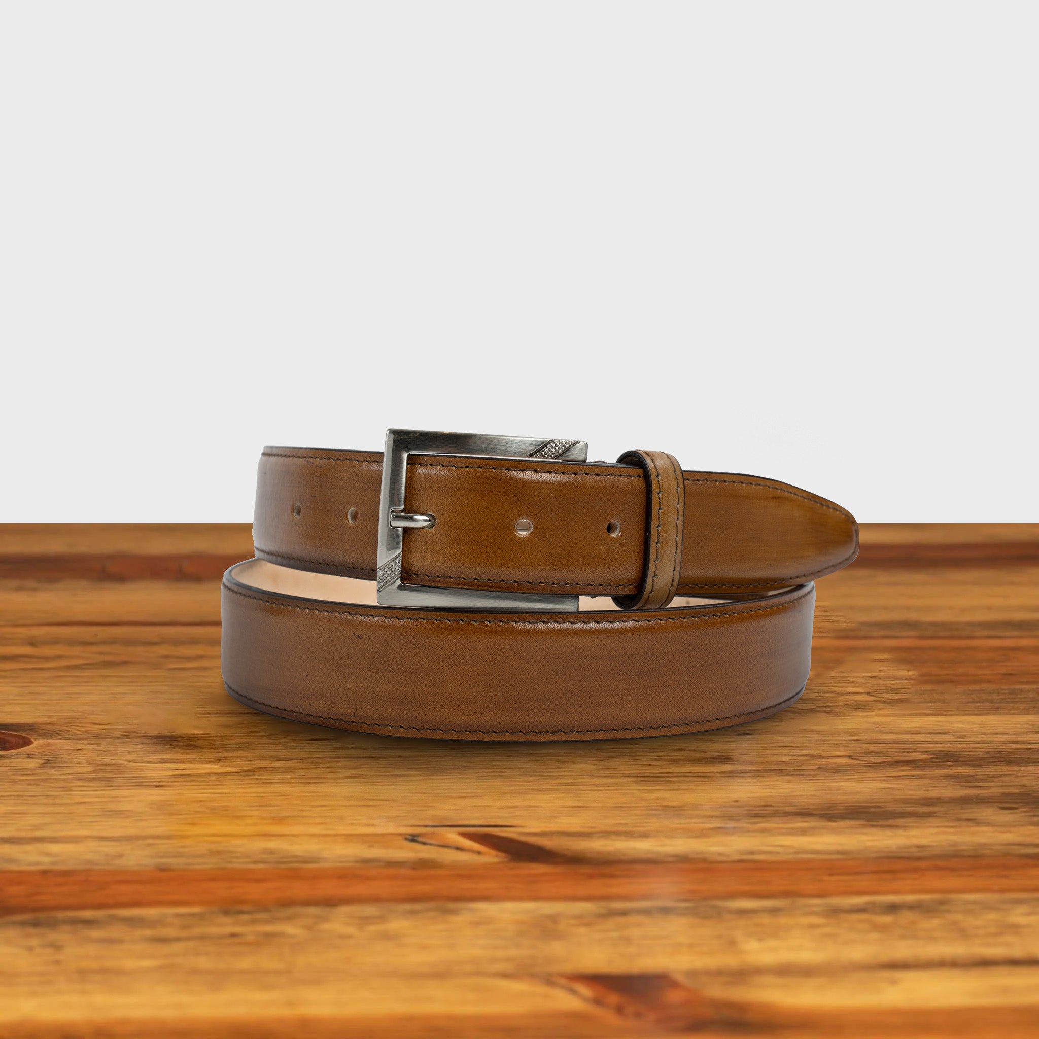 Dark Caramel leather belt with a black buckle on a wooden surface