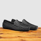 Pair of Black loafer shoe with woven pattern on a wooden surface