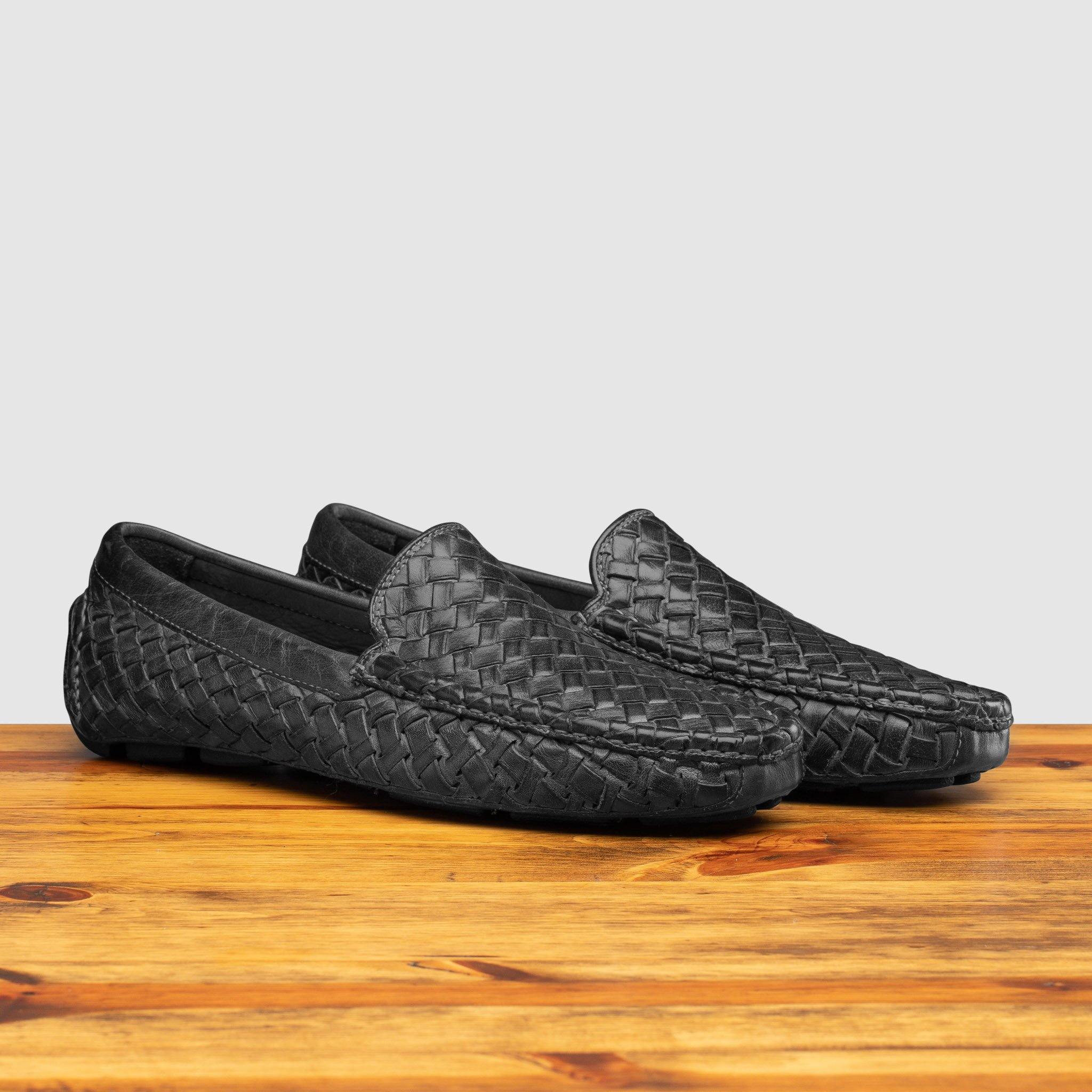 Pair of Black loafer shoe with woven pattern on a wooden surface