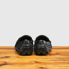 Pair of Black loafer shoe with woven pattern on a wooden surface