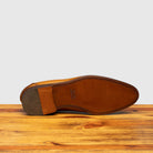 Outsole of Chestnut leather loafer shoe on a wooden surface with a light gray background