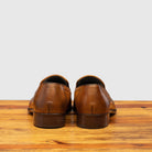Pair of Chestnut leather loafer shoe on a wooden surface with a light gray background