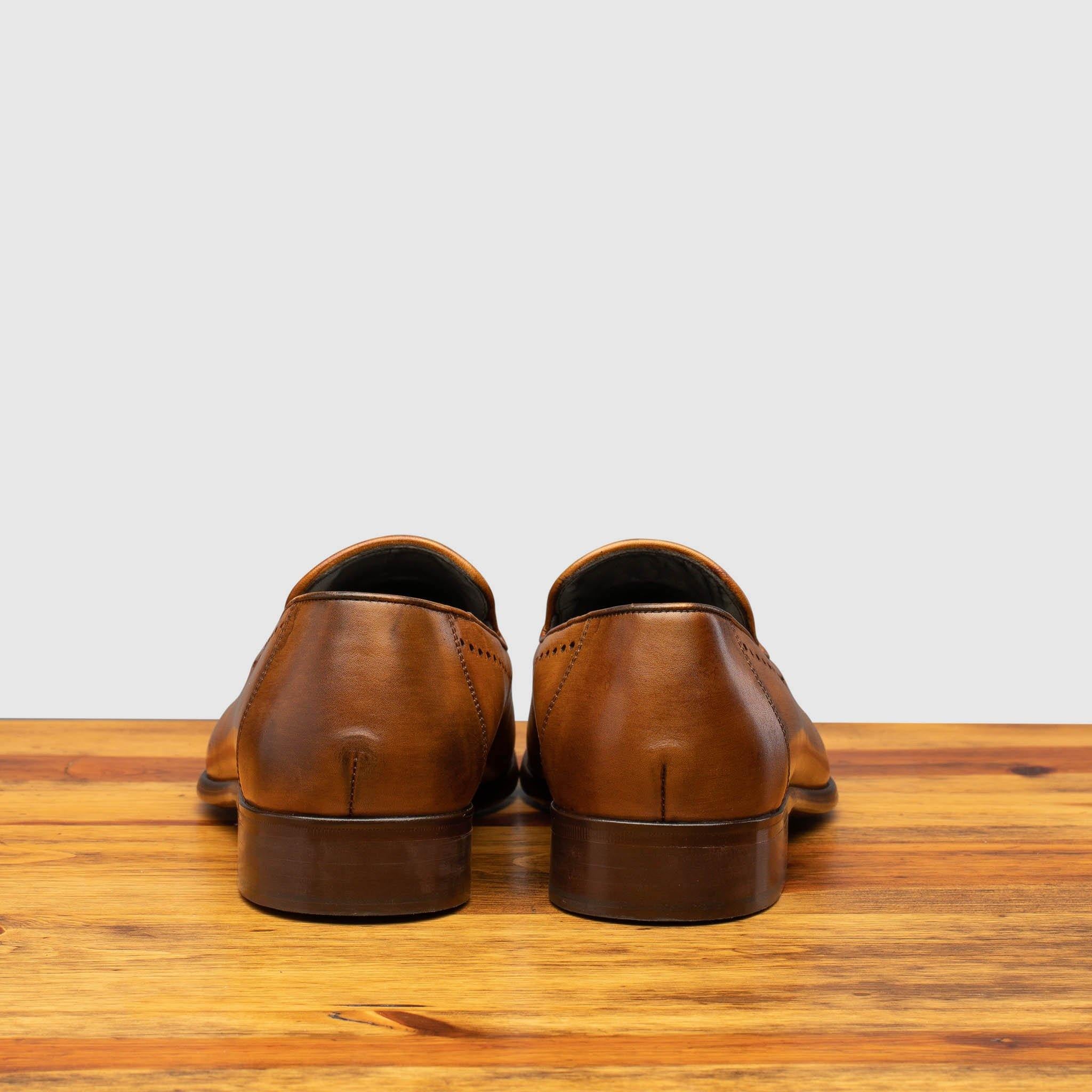 Pair of Chestnut leather loafer shoe on a wooden surface with a light gray background