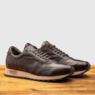 Pair of Brown leather sneaker on a wooden surface with a light gray background