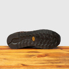 Outsole of Brown leather sneaker on a wooden surface with a light gray background