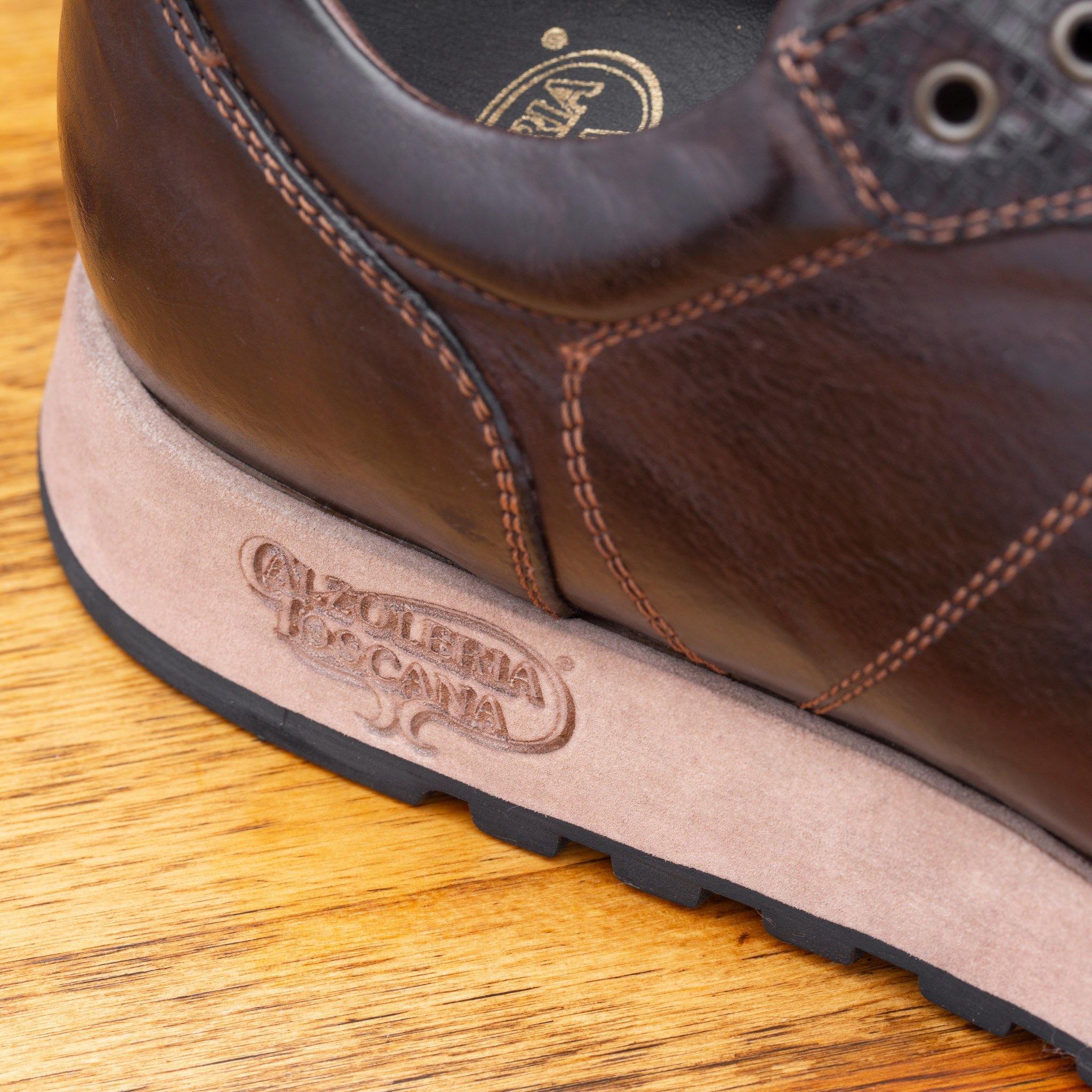 Close view of Brown leather sneaker on a wooden surface