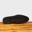 Outsole of Blue leather dress shoe on a wooden surface with a light gray background